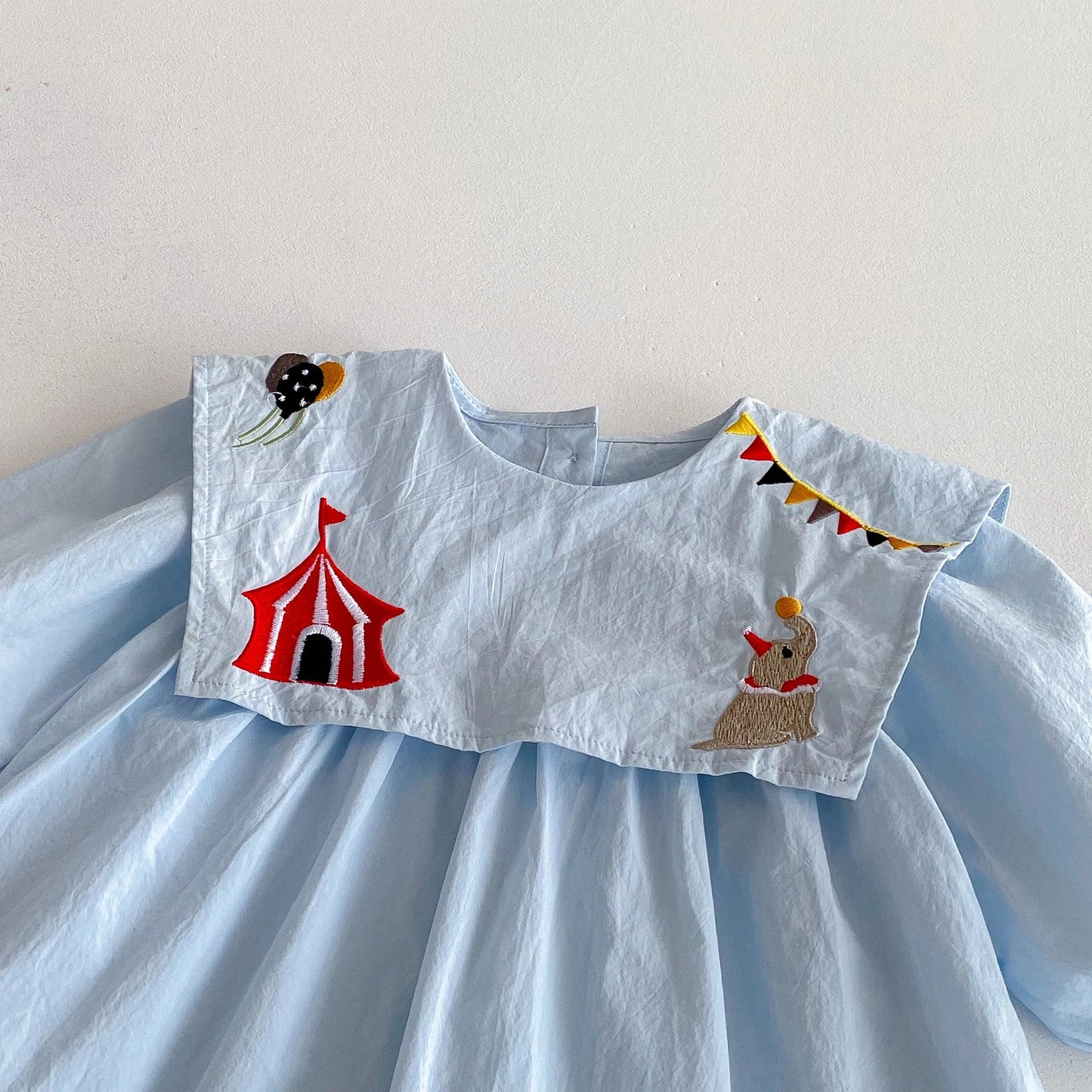 Light blue dress with circus-themed appliqués on a plain background