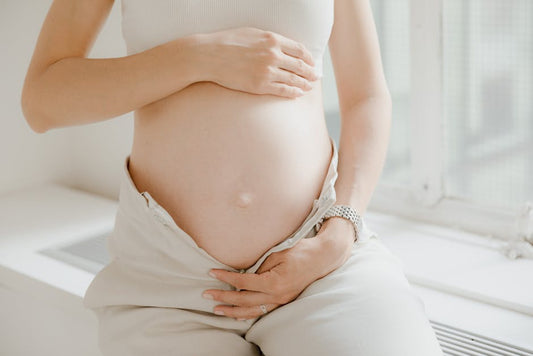 Close-up of a pregnant woman gently holding her belly, symbolizing maternity and motherhood.