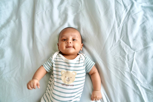 A baby laying on top of a white sheet