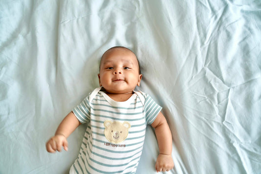 A baby laying on top of a white sheet