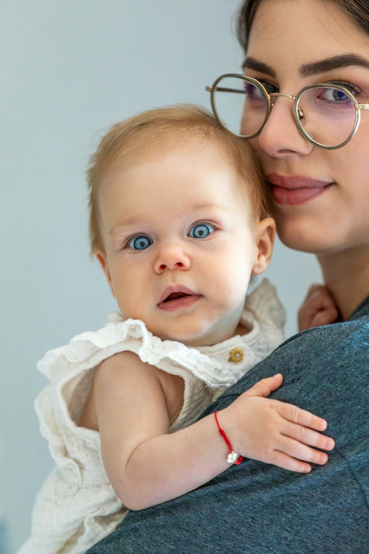 Baby with striking blue eyes held by adult