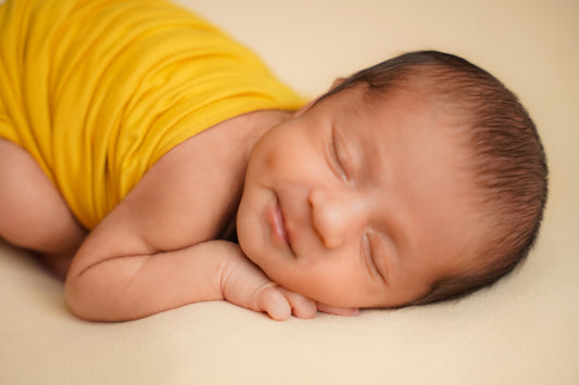 Newborn baby sleeping peacefully in yellow outfit