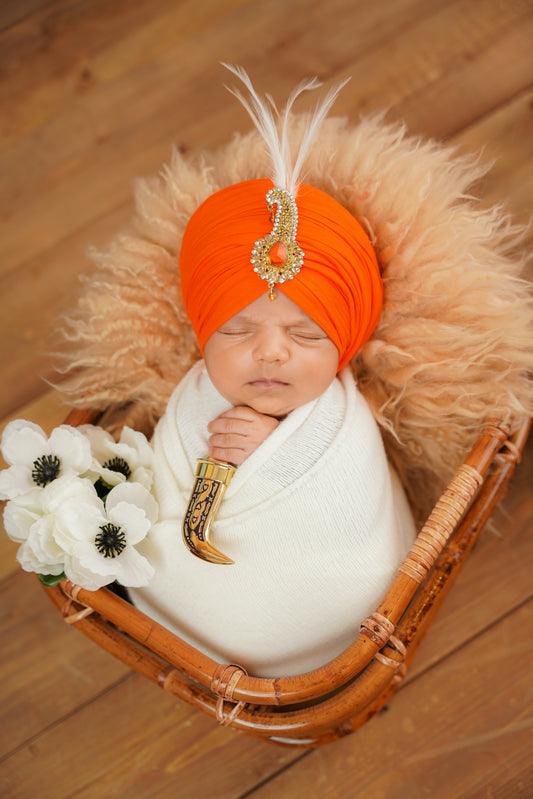 Newborn baby in orange turban with decorative dagger