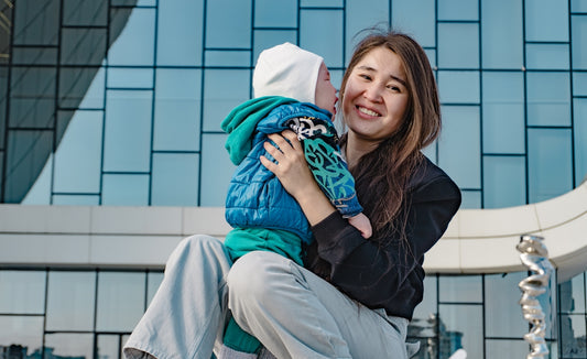 Mother holding her baby in front of a modern building.