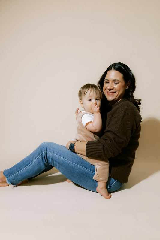 Mother holding her baby on a plain background.