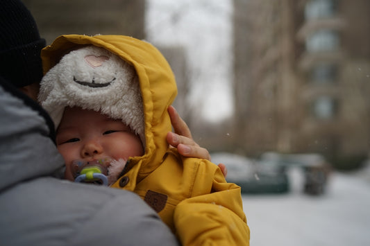 Baby in yellow coat with pacifier in winter