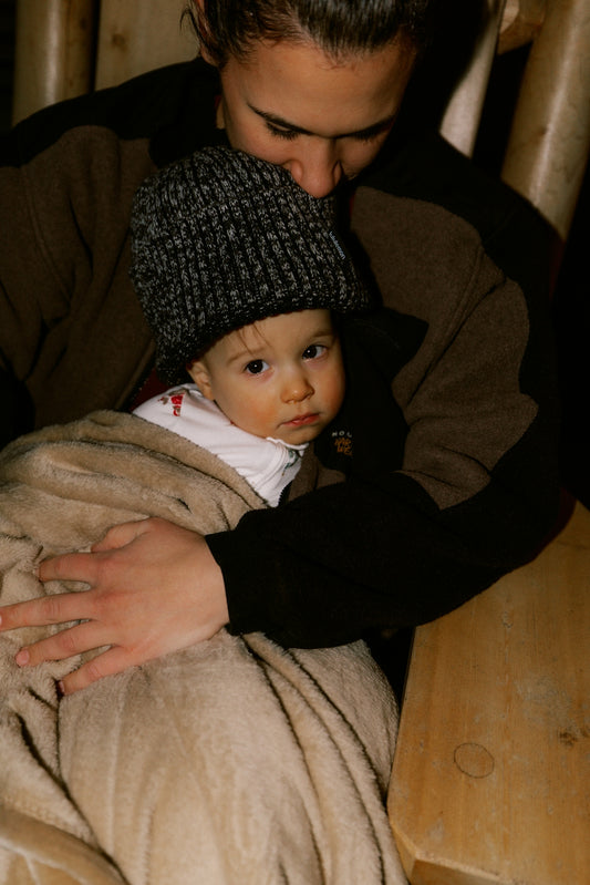 Parent holding a baby wrapped in a blanket.