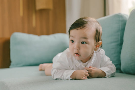 Baby lying on a couch with teal cushions