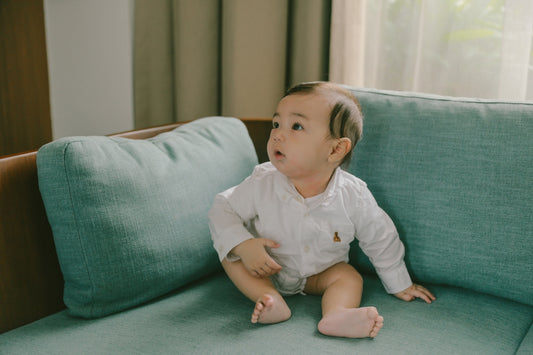 A baby sitting on a teal couch.