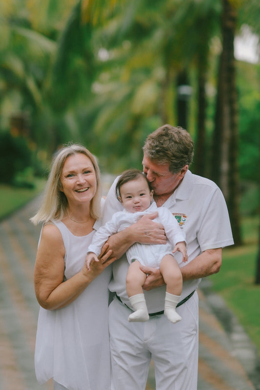 Grandparents holding their baby outdoors