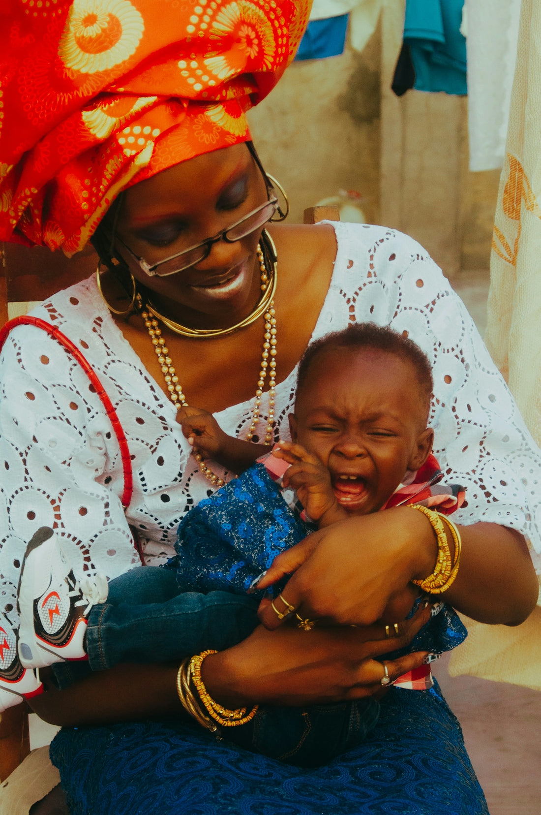 A woman in traditional clothing holds a crying baby.