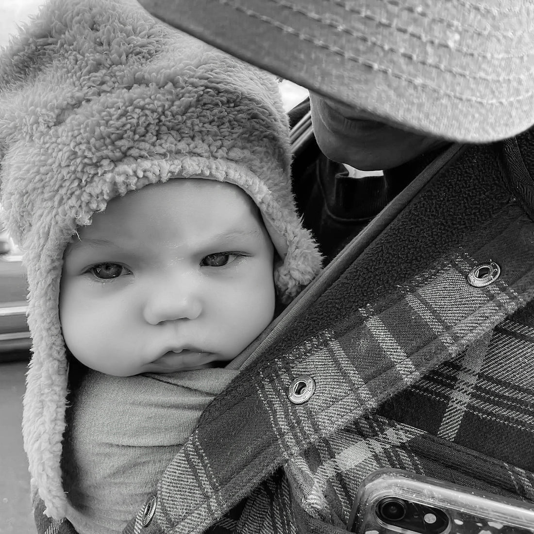 A baby wearing a fuzzy hat looks serious.