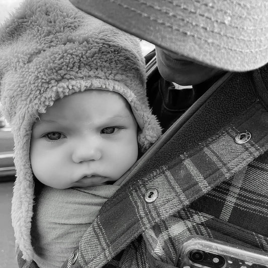 A baby wearing a fuzzy hat looks serious.