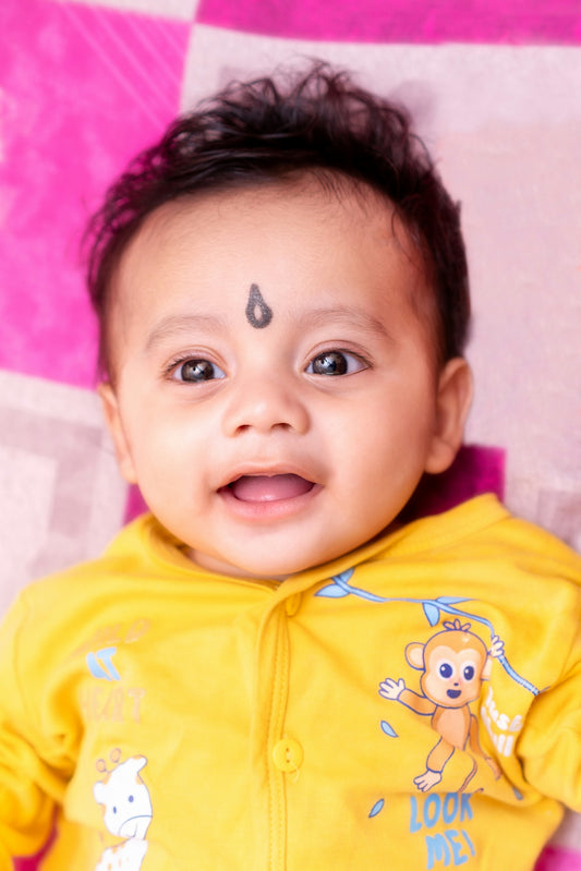 Cute baby smiling with a bindi, wearing yellow