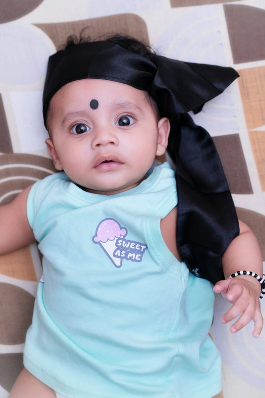Adorable baby with a black headscarf and bindi looking up