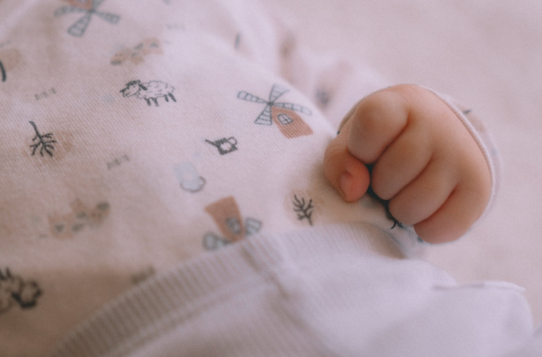 Baby's tiny clenched hand on patterned bodysuit