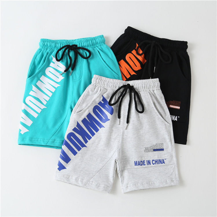 Three casual cotton shorts in teal, gray, and black with drawstrings and bold typographic prints