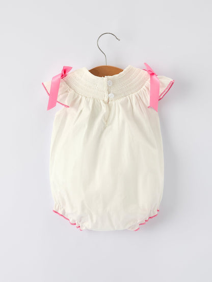 White baby romper with pink trim on a hanger against a white background