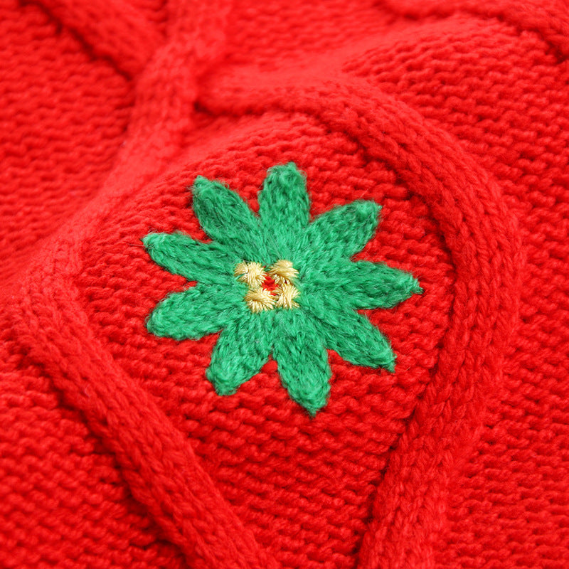 Close-up of red knitted fabric with a green and yellow embroidered flower pattern