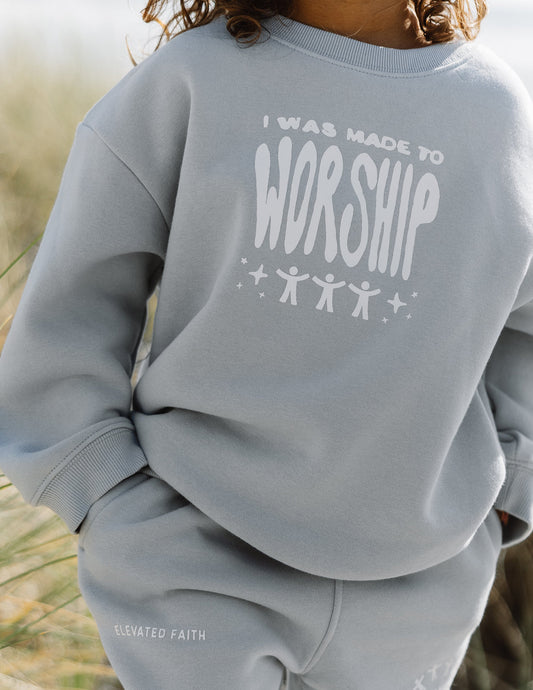 Gray sweatshirt with 'I was made to worship' text worn by a person outdoors.