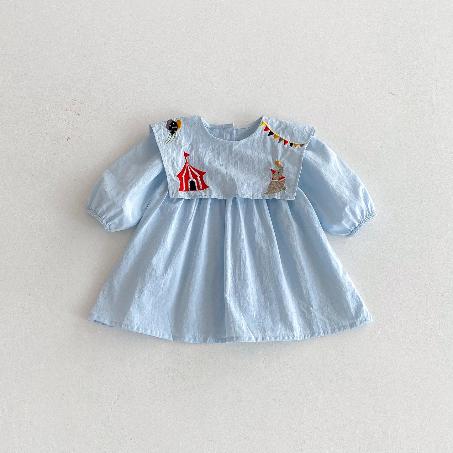Light blue dress with circus-themed appliqué on a white background