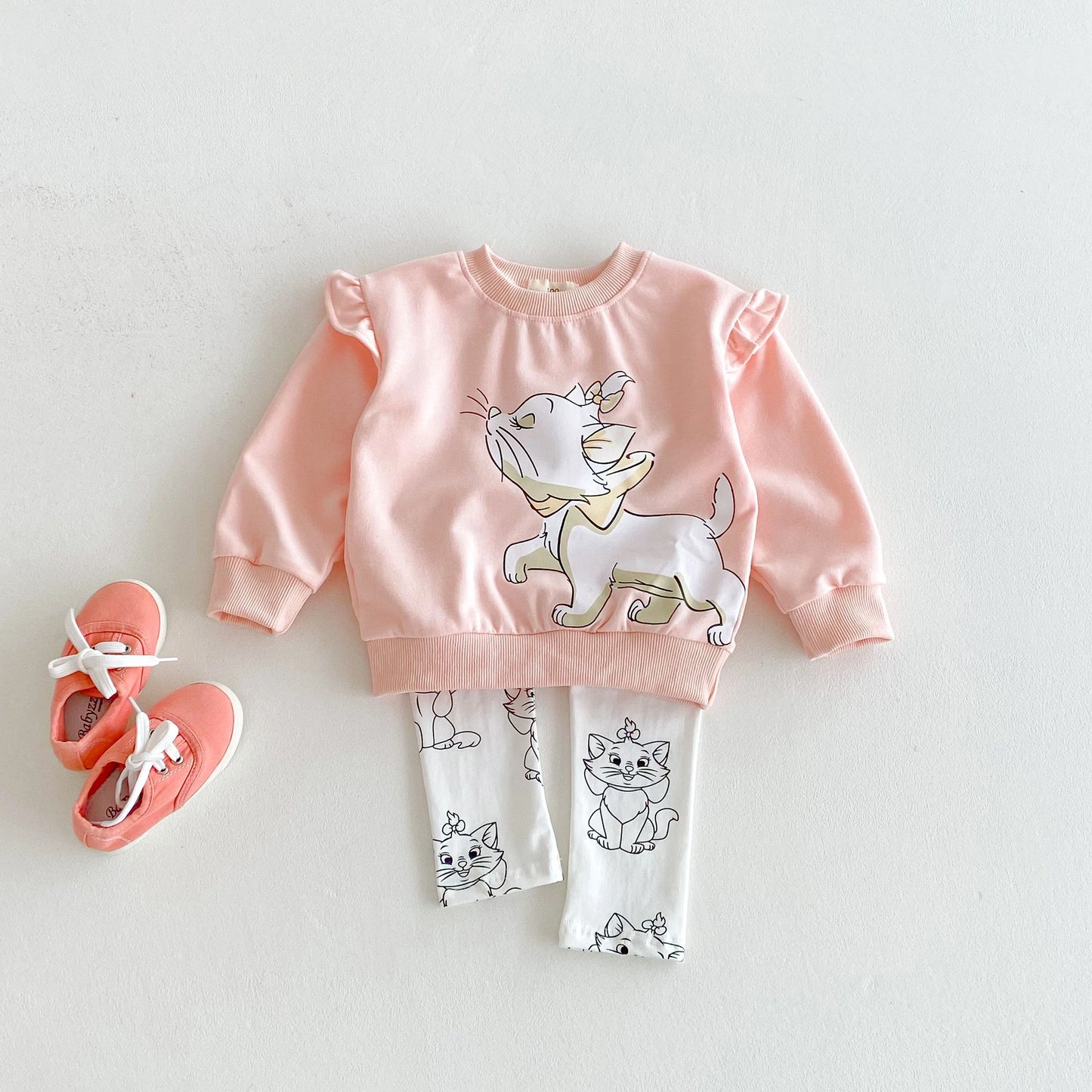 Pink sweatshirt with cat design, white leggings with cat prints, and pink shoes on a light gray background