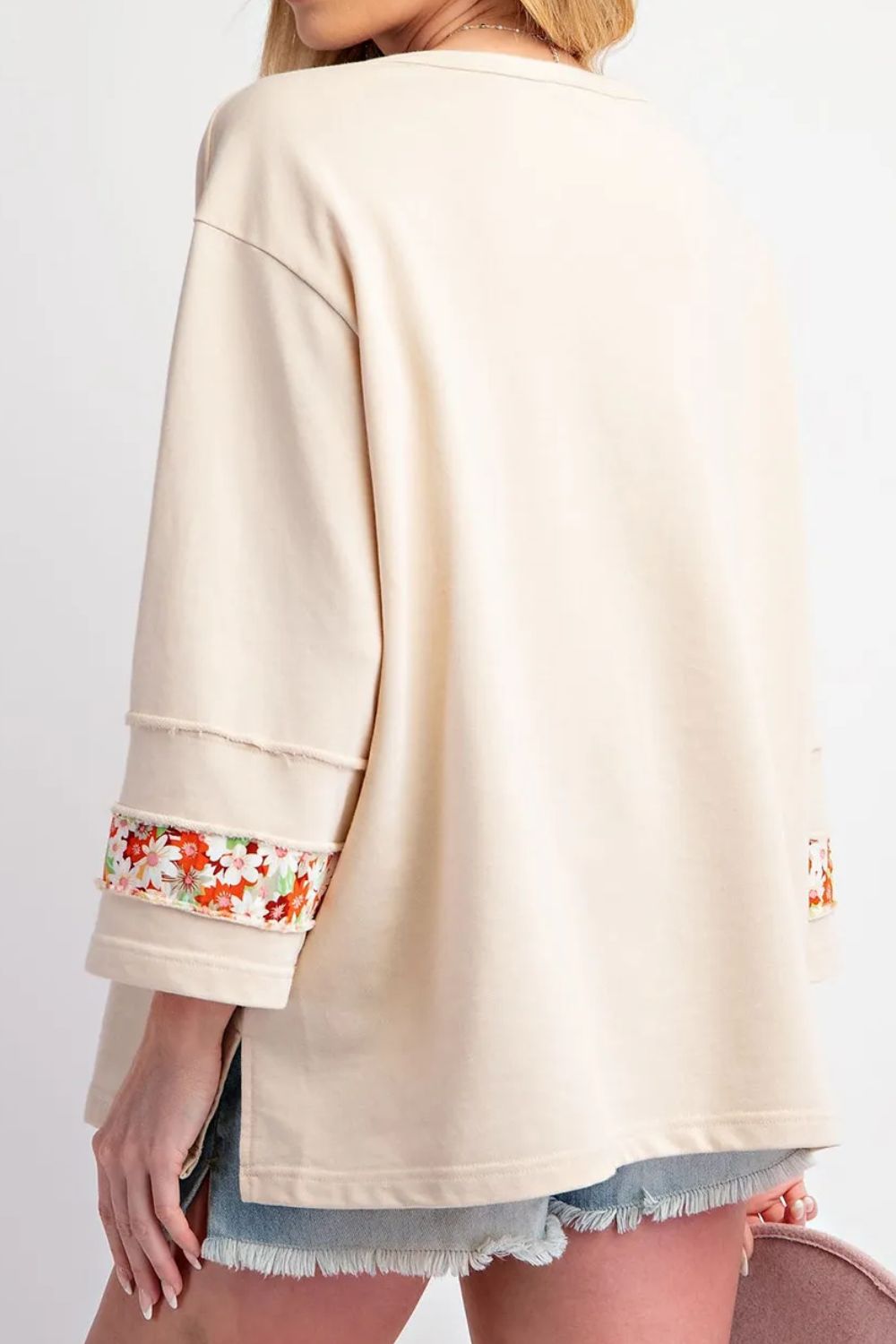 Beige sweatshirt with floral cuffs and hem on a plain background