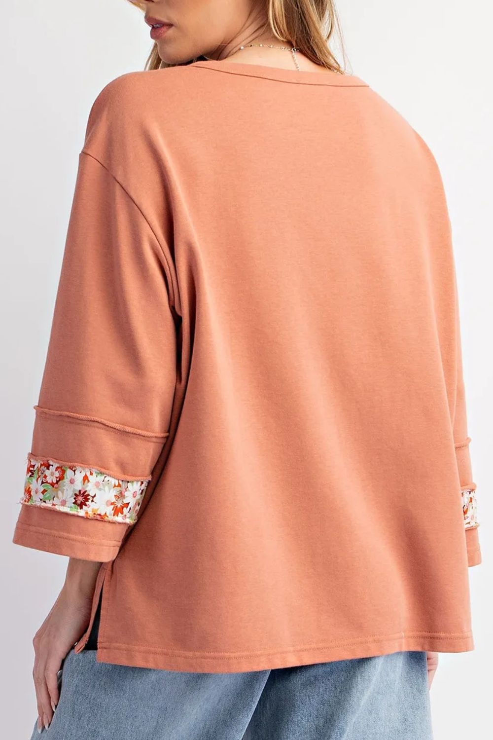 Coral long-sleeve top with floral cuffs on a white background
