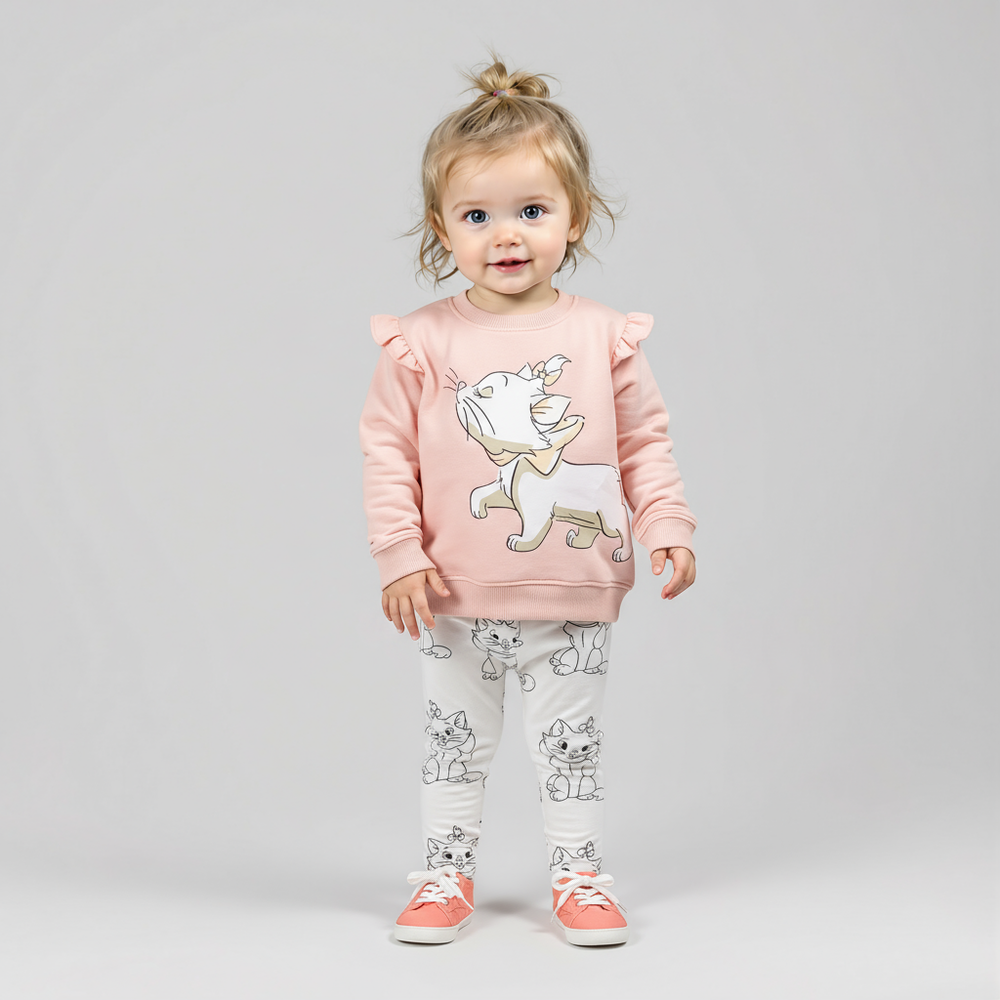 Child wearing a pink sweatshirt with a cartoon design and white pants with cat prints on a gray background