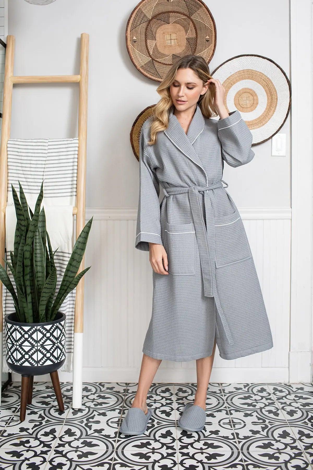 Woman wearing a gray robe standing in a room with decorative elements.