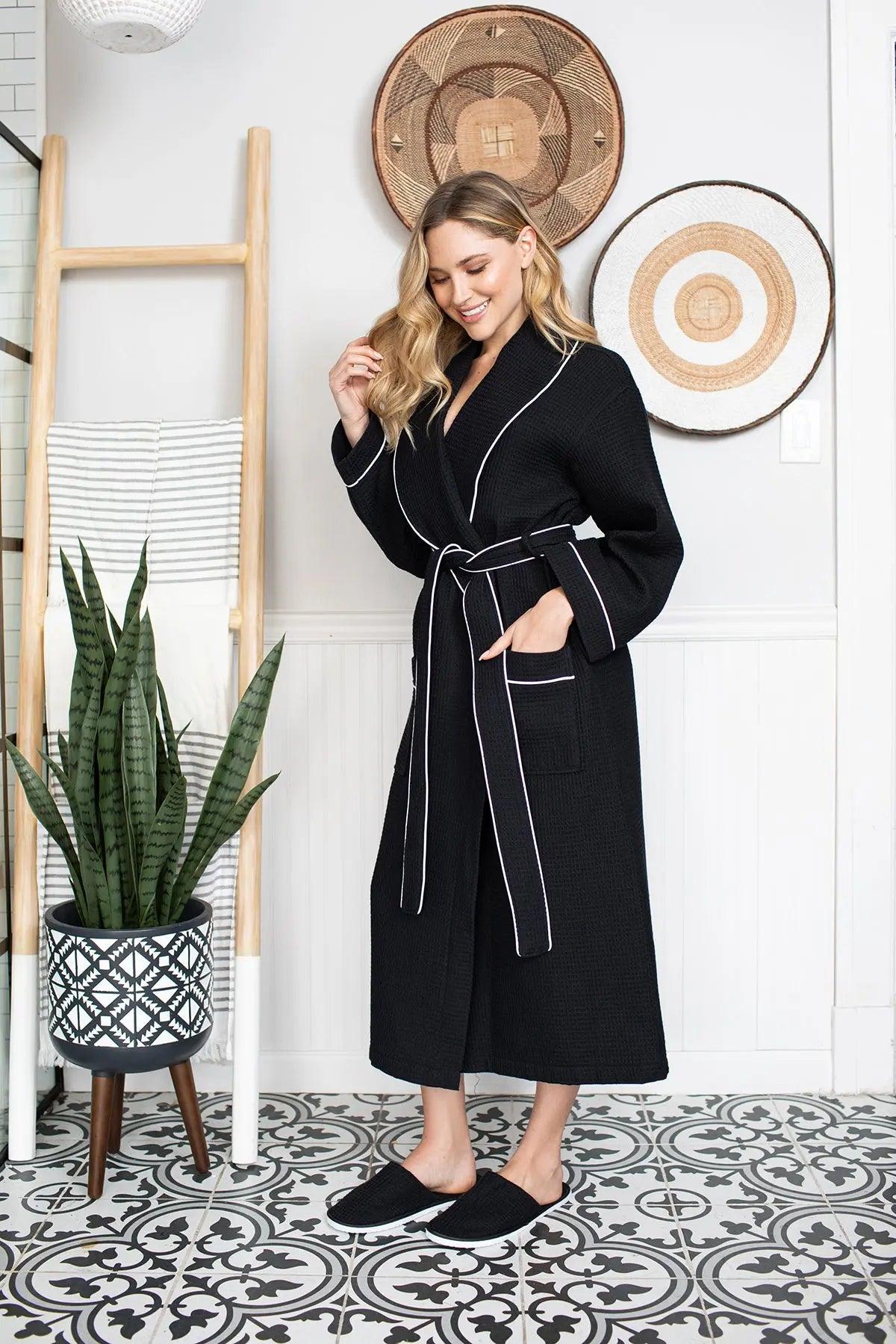 Woman wearing a black robe with white piping in a room with decorative elements.